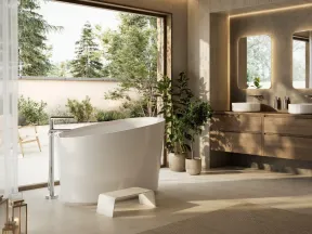 Modern bathroom with freestanding bathtub, wooden vanity, double sinks, plants, and large window showing outdoor greenery.