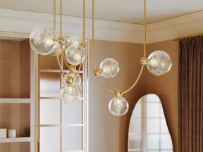 Modern kitchen with marble island, gold spherical pendant lights, floral centerpiece, and tall curved mirror.