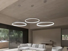 Modern living room with circular pendant lights, beige sofas, a round coffee table, and large glass doors.