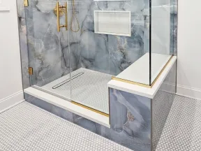 Modern bathroom shower with glass enclosure, gold fixtures, blue marble tiles, and built-in shelves.