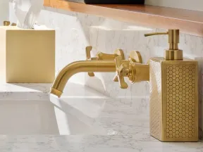Modern bathroom sink with brass faucet, honeycomb patterned soap dispenser, and marble countertop.