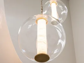 Three modern pendant lights with cylindrical white shades inside clear glass globes hanging from a white ceiling.