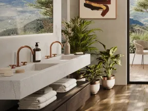 Modern bathroom with double sinks, copper faucets, indoor plants, mountain views, and wood flooring.
