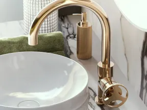 Modern bathroom sink with a sleek round white basin and elegant gold faucet on marble countertop.
