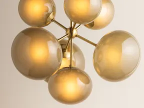 Modern chandelier with seven amber glass globes on brass arms hanging from ceiling.