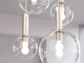Modern pendant lights with clear glass globes and illuminated white bulbs hanging in a bright room.