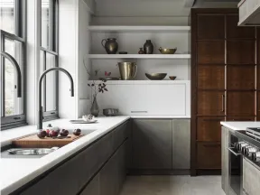 Modern kitchen with gray cabinets, white countertops, wooden pantry, stainless steel stove, and natural light through large windows