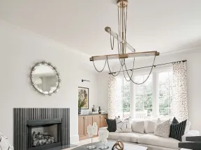 Modern living room with beige sofas, black patterned rug, abstract coffee table, and large windows with curtains.