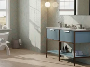 Modern bathroom with freestanding bathtub, blue vanity, wooden floor, and ocean view through large window