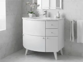 Modern white bathroom vanity with curved design, marble countertop, faucet, mirror, and orchid plant.