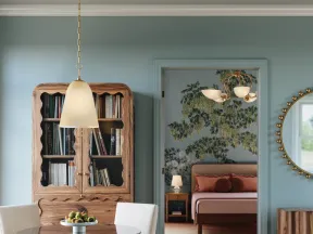 Cozy dining area with round table, white chairs, wooden cabinet, and bedroom with floral wallpaper in the background.