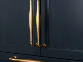 Elegant brass handles on sleek dark blue cabinet doors showcasing modern luxury design.
