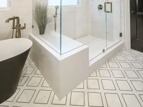 Modern bathroom with glass shower enclosure, freestanding tub, geometric floor tiles, and white marble walls.