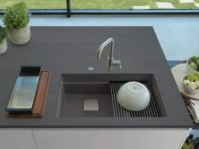 Modern kitchen sink with integrated drying rack on a sleek dark countertop beneath a window