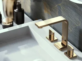 Modern bathroom sink with gold faucet, decorative vases, and dark floral wallpaper background