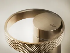 Close-up of a textured metallic ring handle on a sleek, modern Gessi faucet in brushed gold finish.