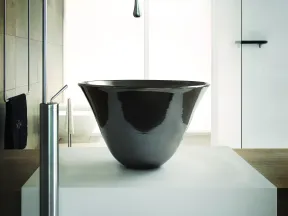 Modern bathroom sink with sleek black basin and tall curved stainless steel faucet on white counter.