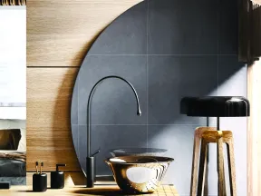 Modern bathroom with round mirror, black faucet, wooden countertop, and stylish lamp in natural light.