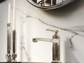 Modern bathroom faucet with ribbed metallic design, black countertop, marble backsplash, and two tall candles.