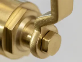 Close-up of a brass hex bolt and wrench on a mechanical component with a blurred background.