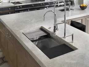 Modern kitchen island featuring a large stone countertop with built-in sink and sleek metal faucet.