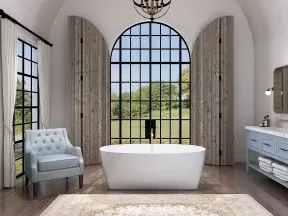 Bright modern bathroom with freestanding tub, large arched window, blue vanity, and light blue armchair
