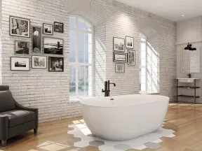 Modern bathroom with white freestanding tub, black armchair, framed photos on white brick walls, and large arched windows.