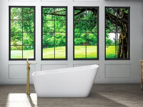 Modern bathroom with freestanding white bathtub and large windows overlooking lush green trees.