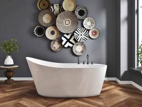 Modern bathroom with freestanding white bathtub, wooden herringbone floor, gray wall, and decorative woven baskets.