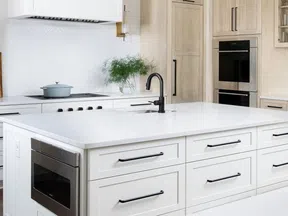 Modern kitchen with white island, black faucet, built-in microwave, wooden cabinets, and stainless steel appliances.