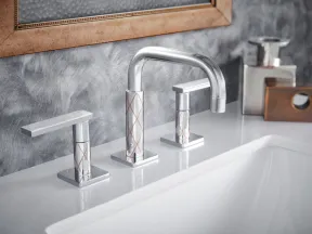 Modern chrome bathroom faucet with geometric pattern on white countertop and textured gray wall.