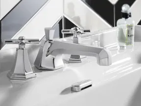 Modern chrome faucet and handles on white sink with black and white chevron tile backsplash.