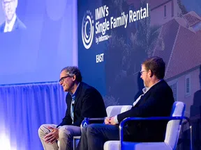 Two men in suits seated on stage discussing at IMN's Single Family Rental East conference event.