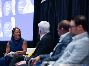 Panel discussion at a professional conference with speakers engaged in conversation on stage.
