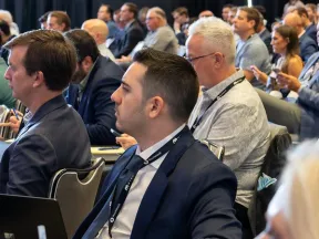 Diverse group of professionals attentively listening at a formal business conference in a large room.