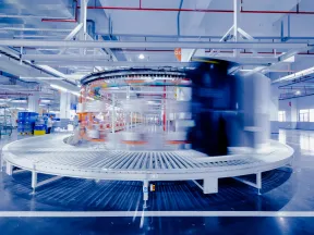 High-speed circular conveyor system in a modern industrial warehouse with blurred motion conveying packages.