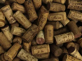 Close-up of numerous used wine corks with various printed labels and dark textured surfaces