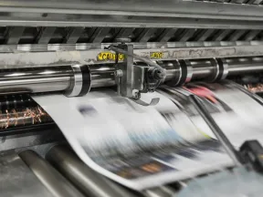 High-speed newspaper printing machine producing blurred moving pages in a press.