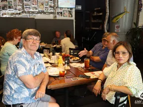 Group of adults enjoying food and drinks together at a casual restaurant table.