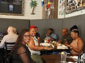 Group of diverse friends enjoying a meal and drinks together in a cozy restaurant with lively atmosphere.