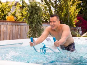 Man exercising on an underwater stationary bike in a backyard pool on a sunny day