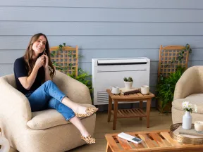 Woman sitting relaxed on a beige armchair in a cozy indoor patio with air conditioner and plants.