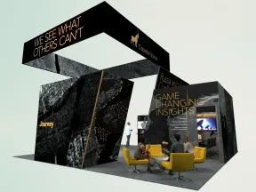 Modern exhibition booth with black and gold design, seating area, and bold text highlighting insights and journey.