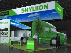 Hyliion green electric truck and trailer displayed at trade show booth with company branding and representatives.