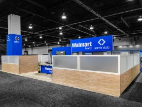 Walmart Realty and Sam's Club booth with blue signage and wood-paneled partitions in large conference hall.