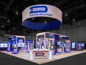 Dover Fueling Solutions trade show booth with fuel pumps and digital displays in a large convention center.