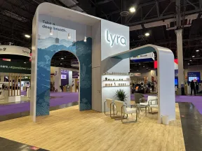 Lyra exhibition booth with blue arch, slogan 'Take a deep breath,' seating area, and modern design at trade show.