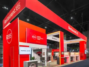 Bright red Restaurant365 trade show booth featuring digital displays, seating, and branding in an exhibition hall.