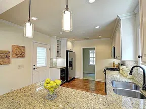 Bright modern kitchen with granite countertops, stainless steel appliances, hardwood floors, and pendant lighting.