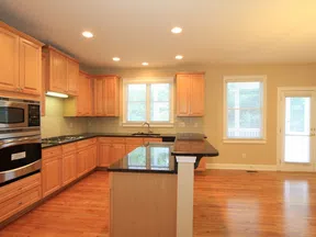 Bright spacious kitchen with wooden cabinets, granite countertops, hardwood floors, and stainless steel appliances.
